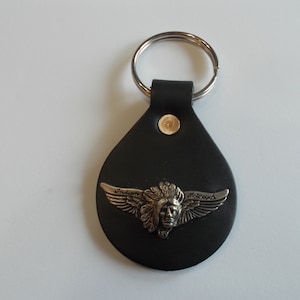 Op de afbeelding: Zwarte leren sleutelhanger met een zilveren Indian Motorcycle logo met een Indiaans hoofd met veren en vleugels.