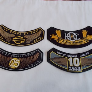 May include: Four Harley Owners Group (HOG) patches with embroidered wings and text. The patches are black with gold and white embroidery. The text on the patches reads "30 Years of HOG 1983-2013", "Harley Owners Group 1983-2008 25", "HOG 10 Year Member", and "Harley Owners Group 10 Year Member".