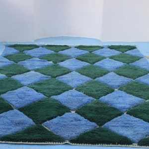 May include: A blue and green checkered rug with a diamond pattern. The rug is made of a soft, plush material.