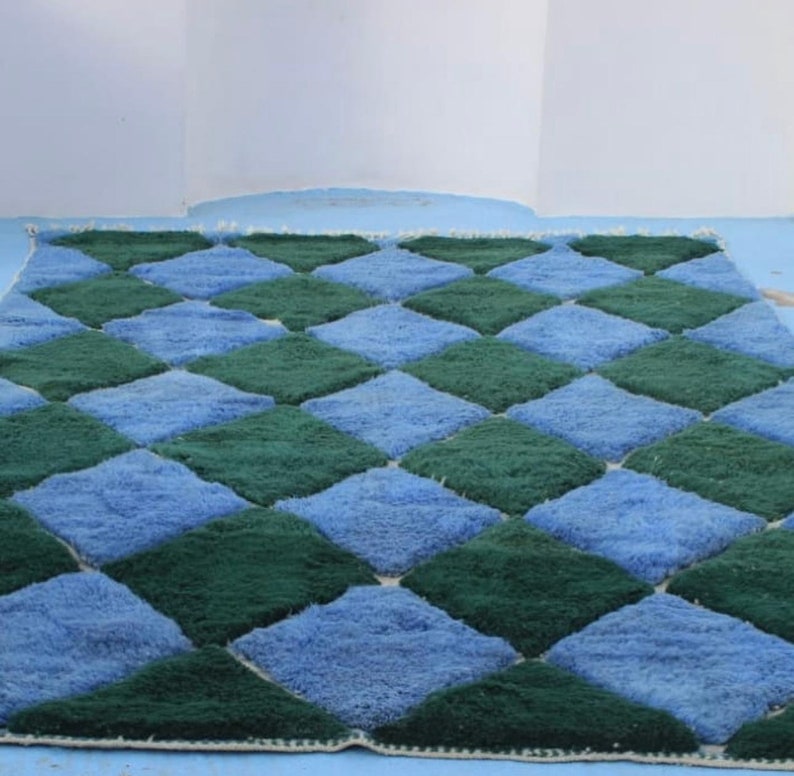 May include: A blue and green checkered rug with a diamond pattern. The rug is made of a soft, plush material.
