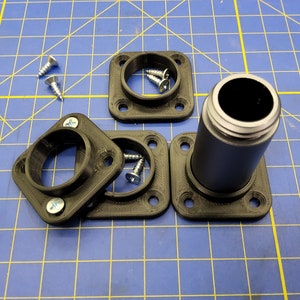 May include: Four black plastic square bases with four screw holes each, and a black plastic cylinder with a silver rim. There are three silver screws on the table.
