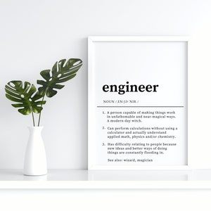 May include: A white framed print with the word "engineer" in black text. The print defines the word "engineer" as a person capable of making things work in unfathomable and near-magical ways, a modern-day witch. It also describes an engineer as someone who can perform calculations without using a calculator and understands applied maths, physics, and/or chemistry. Finally, it states that engineers have difficulty relating to people because new ideas and better ways of doing things are constantly flooding in. The print also includes the phrase "See also: wizard, magician."