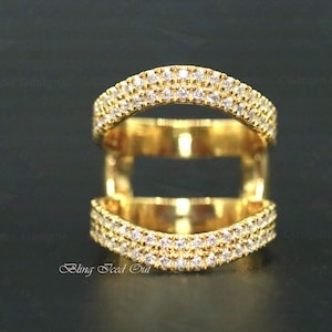 Może przedstawiać: Złoty pierścionek z trzema obręczami, każda ozdobiona przezroczystymi cyrkoniami. Obręcze są ułożone jedna na drugiej, tworząc unikalny i stylowy wzór.