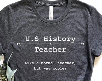 May include: A dark gray t-shirt with white text that reads "U.S. History Teacher Like a normal teacher, but way cooler".