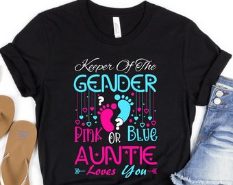 May include: Black t-shirt with the text "Keeper of the Gender Pink or Blue Auntie Loves You" in pink, blue, and white. The design also includes a pink and blue footprint with a question mark.