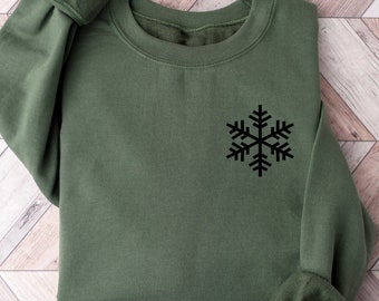 May include: A green sweatshirt with a black snowflake design on the front.