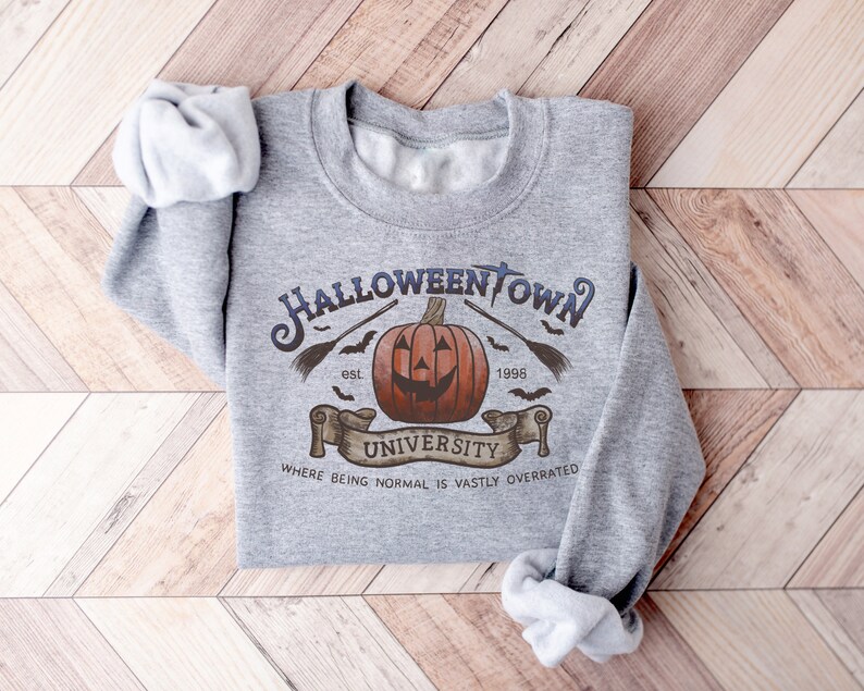 May include: Gray sweatshirt with a Halloweentown University graphic. The graphic features a jack-o'-lantern, bats, a broom, and the text "Halloweentown University est. 1998" and "Where being normal is vastly overrated".