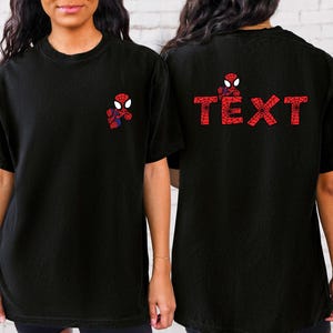 May include: Two black t-shirts featuring a red and blue Spiderman graphic. One shirt has the graphic on the front and the other has the graphic on the back with the text "TEXT".