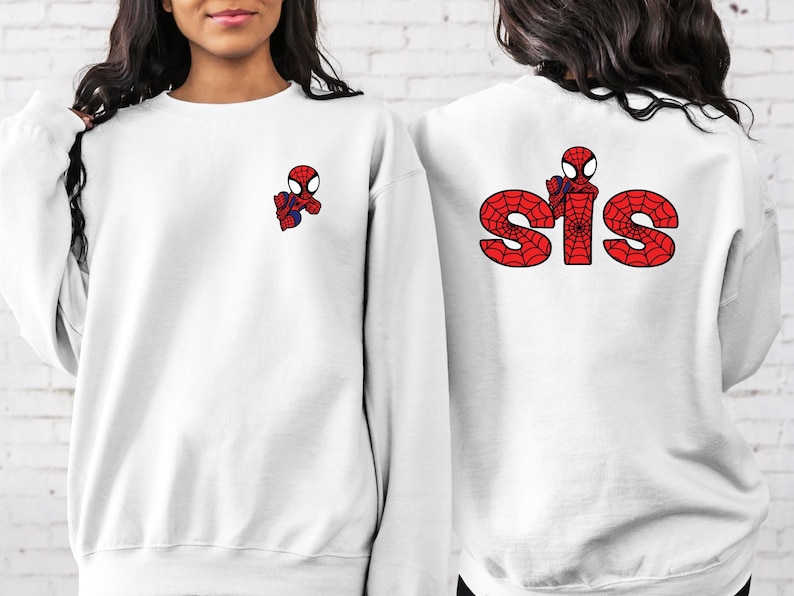 May include: Two white sweatshirts featuring a red and blue Spiderman graphic. One sweatshirt has the word "SIS" in red with a spiderweb design.