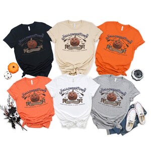 May include: Six different color t-shirts with a Halloweentown University graphic featuring a jack-o-lantern, bats, and the text "Where being normal is vastly overrated".