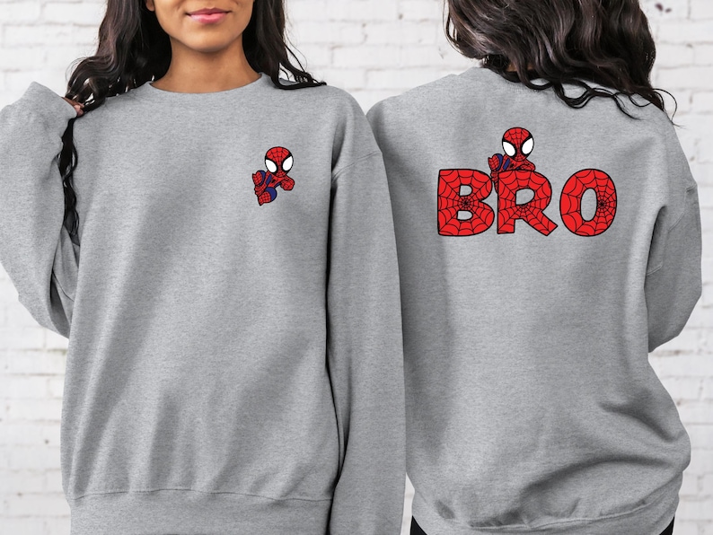 May include: Two grey sweatshirts with a Spiderman design. One sweatshirt has a small Spiderman graphic on the left chest and the other sweatshirt has a larger Spiderman graphic with the word "BRO" on the back.