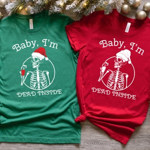 May include: Two Christmas themed t-shirts with a skeleton wearing a Santa hat and holding a drink. The green shirt says "Baby, I'm Dead Inside" and the red shirt says "Baby, I'm Dead Inside".