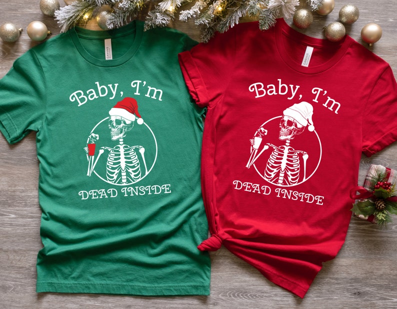 May include: Two Christmas themed t-shirts with a skeleton wearing a Santa hat and holding a drink. The green shirt says "Baby, I'm Dead Inside" and the red shirt says "Baby, I'm Dead Inside".