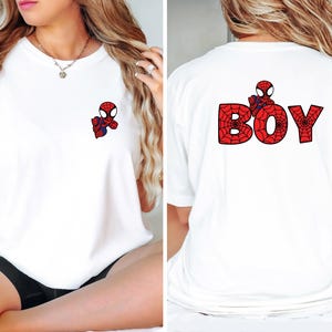 May include: White t-shirt with a small Spiderman graphic on the front pocket and the word "BOY" with a Spiderman design on the back.