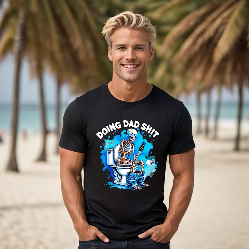 May include: Black t-shirt with the phrase "DOING DAD SHIT" above a cartoon skeleton on a toilet, using a phone. The design features blue watercolor accents. The shirt is worn by a person.