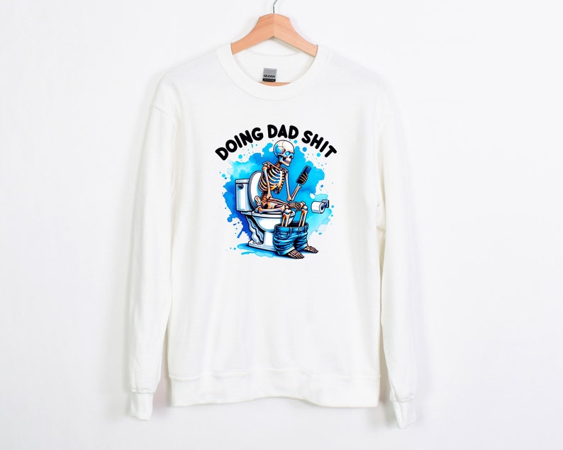 May include: White sweatshirt with the phrase "DOING DAD SHIT" above a colorful graphic of a skeleton on a toilet, using a phone. The graphic has blue watercolor-style accents.