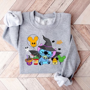 May include: Gray sweatshirt with a blue Stitch character wearing a witch hat and holding a small green Stitch. The design includes a Mickey Mouse balloon, a ghost, and other Halloween-themed elements.