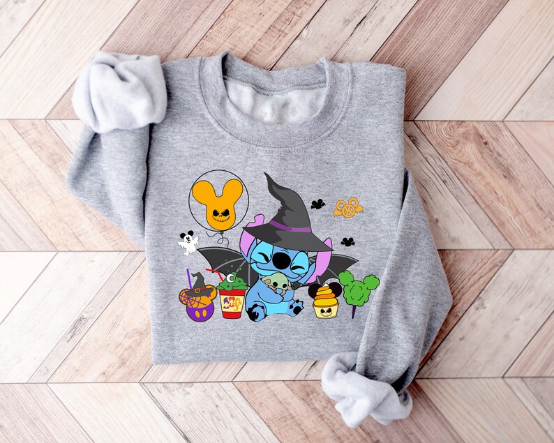 May include: Gray sweatshirt with a blue Stitch character wearing a witch hat and holding a small green Stitch. The design includes a Mickey Mouse balloon, a ghost, and other Halloween-themed elements.