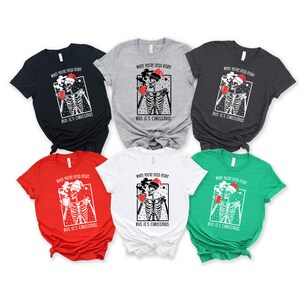 May include: Six different color t-shirts featuring a skeleton wearing a Santa hat and holding a mug. The text on the shirts reads "When you're dead inside but it's Christmas".