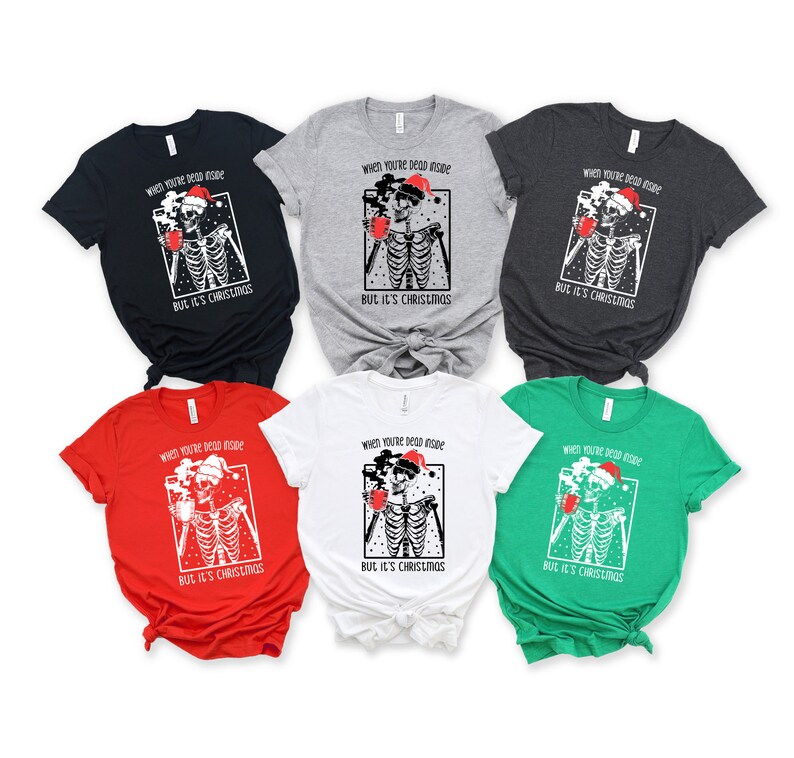 May include: Six different color t-shirts featuring a skeleton wearing a Santa hat and holding a mug. The text on the shirts reads "When you're dead inside but it's Christmas".