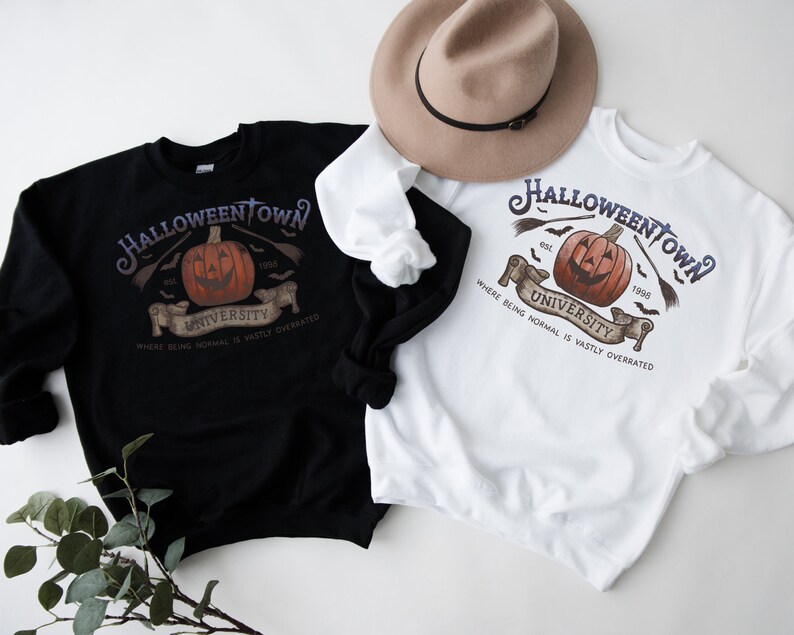 May include: Two sweatshirts with a Halloween Town University graphic. The graphic features a jack-o-lantern with a toothy grin, bats, and the text "Halloween Town University" with the years "est. 1990" and "1996". The sweatshirts are black and white.