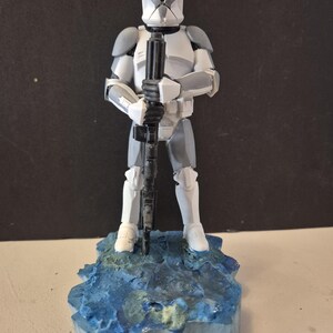 Pu&ograve; includere: Statuetta dettagliata di un soldato corazzato bianco e grigio che tiene un fucile nero. La figura &egrave; su una base strutturata blu e verde. Il casco ha una visiera verde. &Egrave; un oggetto da collezione.