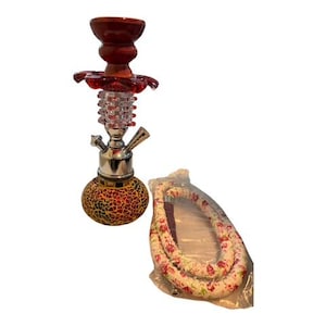 May include: A decorative hookah with a red wooden top and a glass body with a mosaic pattern. The hookah has a silver metal stem and a floral patterned hose. The hookah is designed for smoking.