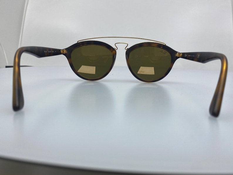 May include: Tortoise shell sunglasses with gold accents and brown lenses. The sunglasses have a thin metal bridge and a wire frame.