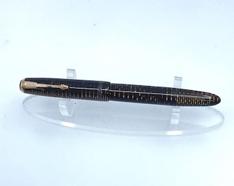 May include: A vintage fountain pen with a black and gold striped pattern. The pen has a gold-colored nib and a gold arrow design on the clip. The pen is displayed on a clear acrylic stand.