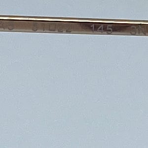 Puede incluir: Primer plano de una banda de metal dorado con la inscripci&oacute;n "59745 3 1022 145 3N".