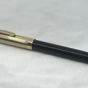 May include: A gold and black fountain pen with a gold cap and a black barrel.