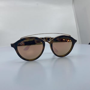 May include: Tortoise shell sunglasses with a gold metal bridge and rose gold mirrored lenses.