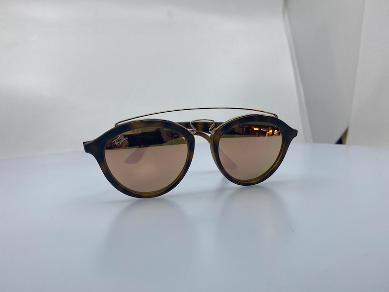 May include: Tortoise shell sunglasses with a gold metal bridge and rose gold mirrored lenses.