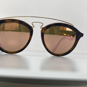 May include: Tortoise shell sunglasses with a gold metal frame and rose gold mirrored lenses.