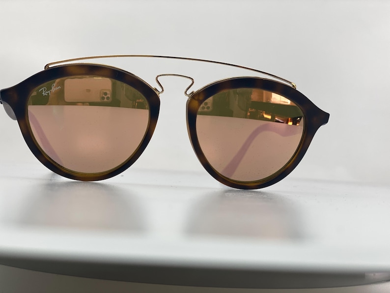 May include: Tortoise shell sunglasses with a gold metal frame and rose gold mirrored lenses.