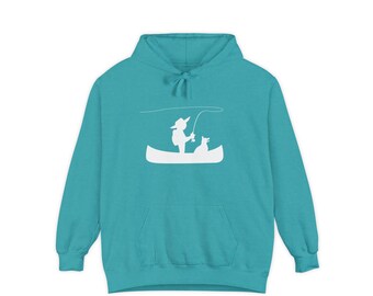 Puede incluir: Sudadera con capucha de color turquesa con un gráfico blanco de una persona pescando en canoa con un perro. La sudadera tiene una capucha con cordón y un bolsillo delantero. El diseño es sencillo y limpio, ideal para uso casual.