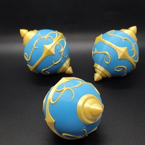 May include: Three blue and gold decorative ornaments with intricate designs. The ornaments are round with a pointed top and bottom.