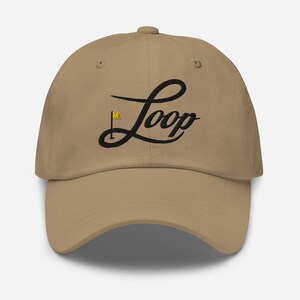 May include: A tan baseball cap with a black embroidered logo that says "Loop" with a small gold golf flag.