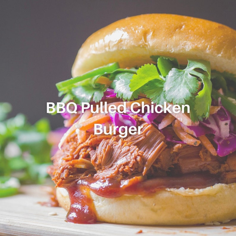 Puede incluir: Primer plano de una hamburguesa de pollo desmenuzado a la barbacoa en un pan con col roja, zanahorias ralladas y cilantro. La hamburguesa est&aacute; cubierta con salsa BBQ.