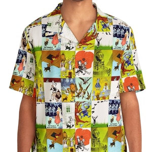 Op de afbeelding: Een wit overhemd met korte mouwen en knopen met een kleurrijk patroon van illustraties uit The Wizard of Oz. Het shirt heeft een kraag en een knoopsluiting aan de voorkant.