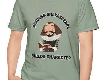 May include: A sage green t-shirt featuring a cartoon illustration of William Shakespeare reading a book. The text "Reading Shakespeare Builds Character" is printed on the shirt.