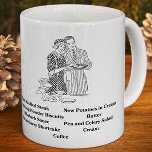 Könnte beinhalten: Weiße Keramiktasse mit einer Schwarz-Weiß-Illustration eines Paares und einem Menü. Das Menü enthält Gerichte wie gebratenes Steak, Kekse und Erdbeerkuchen. Die Tasse steht auf einer Holzoberfläche mit Tannenzapfen.