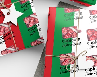 May include: Gift wrapping paper with a repeating pattern of Italian cured meat, capicola, on a white background with the words "capicola / gab-a-gool" printed on the paper. The paper is wrapped around a gift box with a green, white, and red Italian flag design.