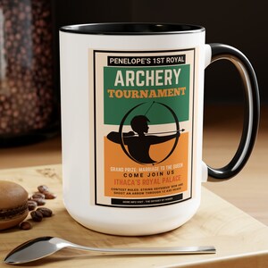 May include: White ceramic mug with a black rim and handle. The mug features a vintage-style poster design with the text "PENELOPE'S 1ST ROYAL ARCHERY TOURNAMENT" and an illustration of a person holding a bow and arrow.