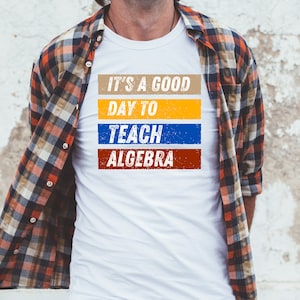 May include: White t-shirt with a colourful graphic that says "It's a good day to teach algebra".