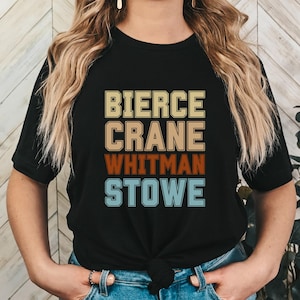 May include: Black t-shirt with a vintage-style design featuring the names "Bierce", "Crane", "Whitman", and "Stowe" in colorful block letters.