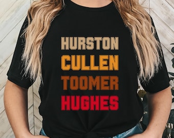 Puede incluir: Camiseta negra con los nombres "Hurston", "Cullen", "Toomer" y "Hughes" impresos en un estilo retro con fondos de colores diferentes.