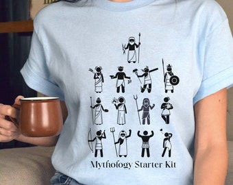 May include: Light blue t-shirt featuring a black and white graphic of various Greek gods and goddesses. The graphic includes the text "Mythology Starter Kit".