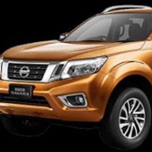 Könnte beinhalten: Ein bronzefarbener Nissan Navara Pickup-Truck vor schwarzem Hintergrund. Das Fahrzeug hat einen verchromten Kühlergrill, Scheinwerfer und Trittbretter. Die Räder sind schwarz mit silbernen Akzenten. Die Ladefläche des Trucks ist ebenfalls sichtbar.