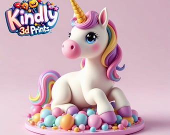 Puede incluir: Figura de unicornio blanco con cuerno dorado, melena y cola arcoíris y ojos azules. El unicornio está sentado sobre una base rosa rodeada de esferas de colores. El texto "Kindly 3D Prints" está en la esquina superior izquierda.